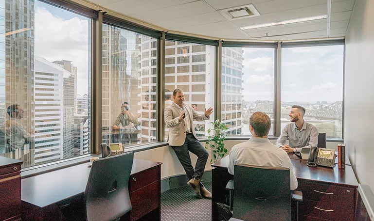 Business leaders engage in a productive meeting inside a Servcorp office featuring panoramic downtown views.
