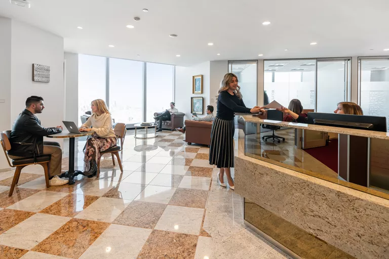 Modern coworking at Williams Tower, Houston, where a receptionist handles mail professionally to the client.